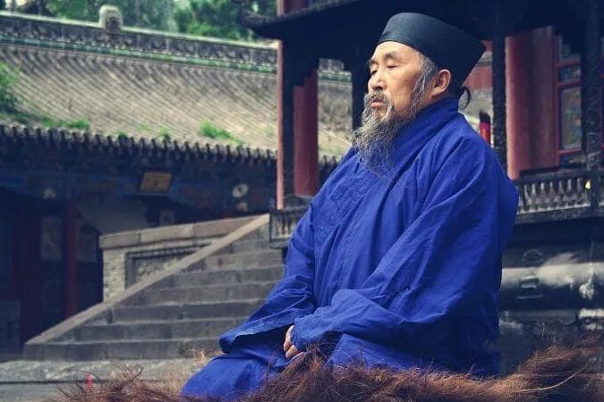 Taoist monk in meditation posture, practicing internal alchemy as part of a Qigong routine. Related to Qigong classes online, Qigong classes in Lisbon. Monaco taoista in posizione di meditazione, praticando alchimia interna come parte di una routine di Qigong. Lezioni di Qigong online, corso di Qigong in Italia