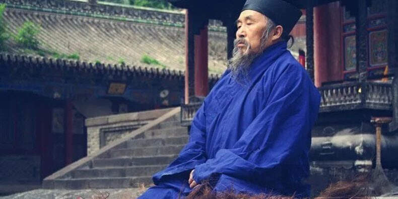 Taoist monk in meditation posture, practicing internal alchemy as part of a Qigong routine. Related to Qigong classes online, Qigong classes in Lisbon. Monaco taoista in posizione di meditazione, praticando alchimia interna come parte di una routine di Qigong. Lezioni di Qigong online, corso di Qigong in Italia